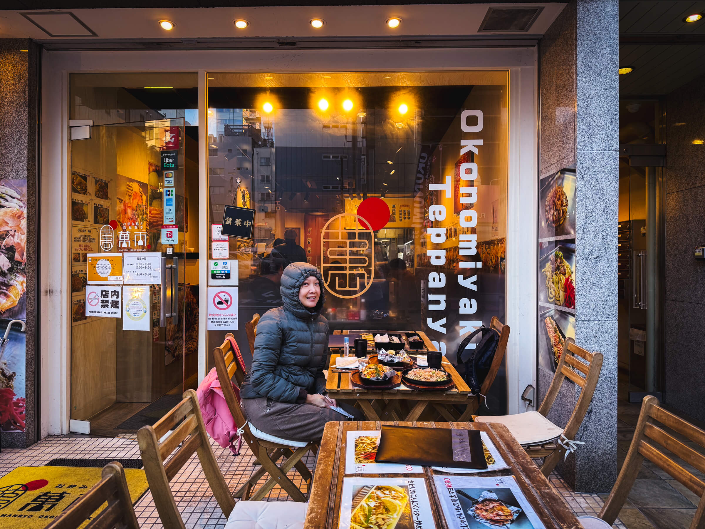 photo of my partner eating at an outdoor okonomiyaki restaurant