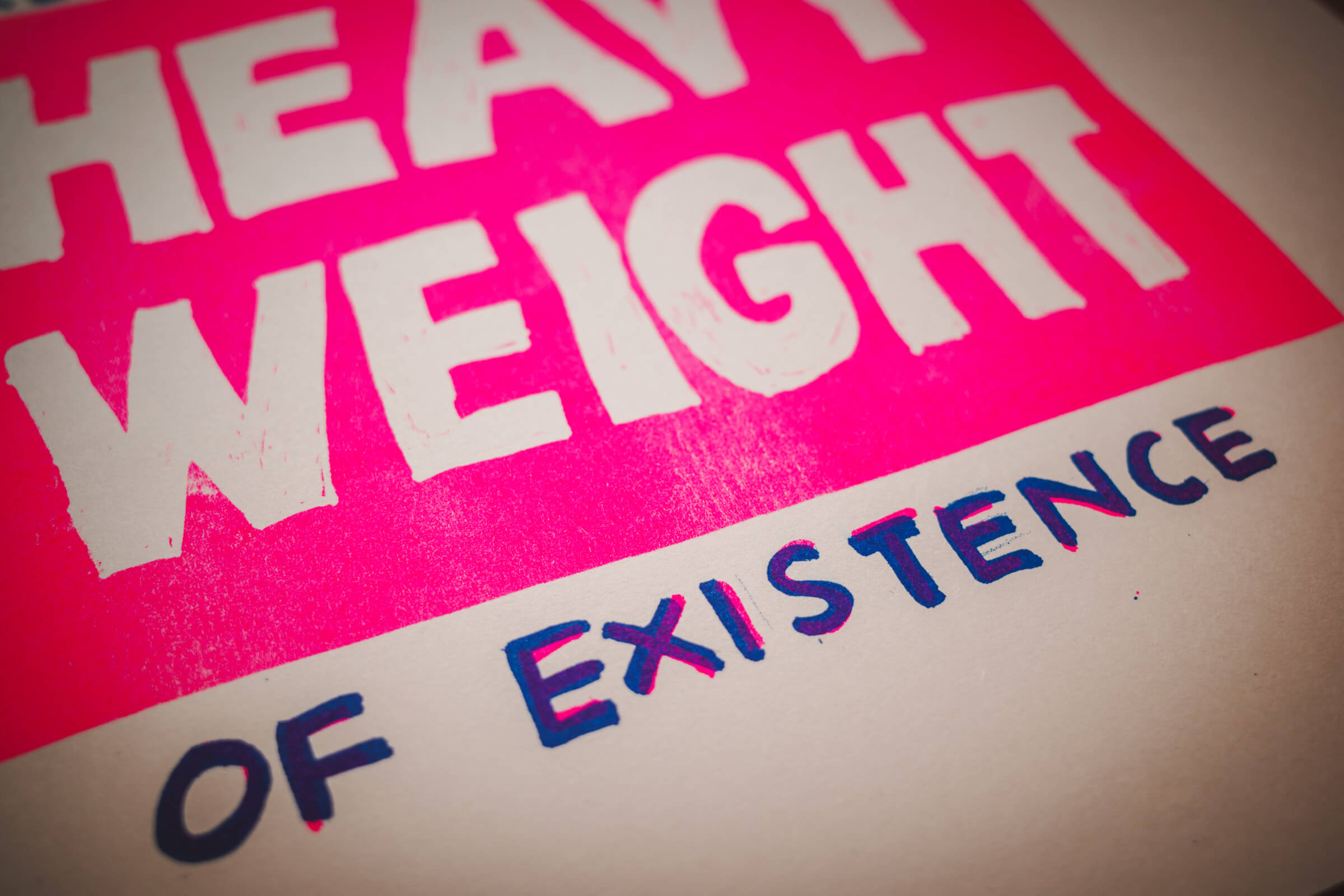 close up of the pink block with words "heavy weight", and the words "of existence" printed with overlapping blue and pink ink