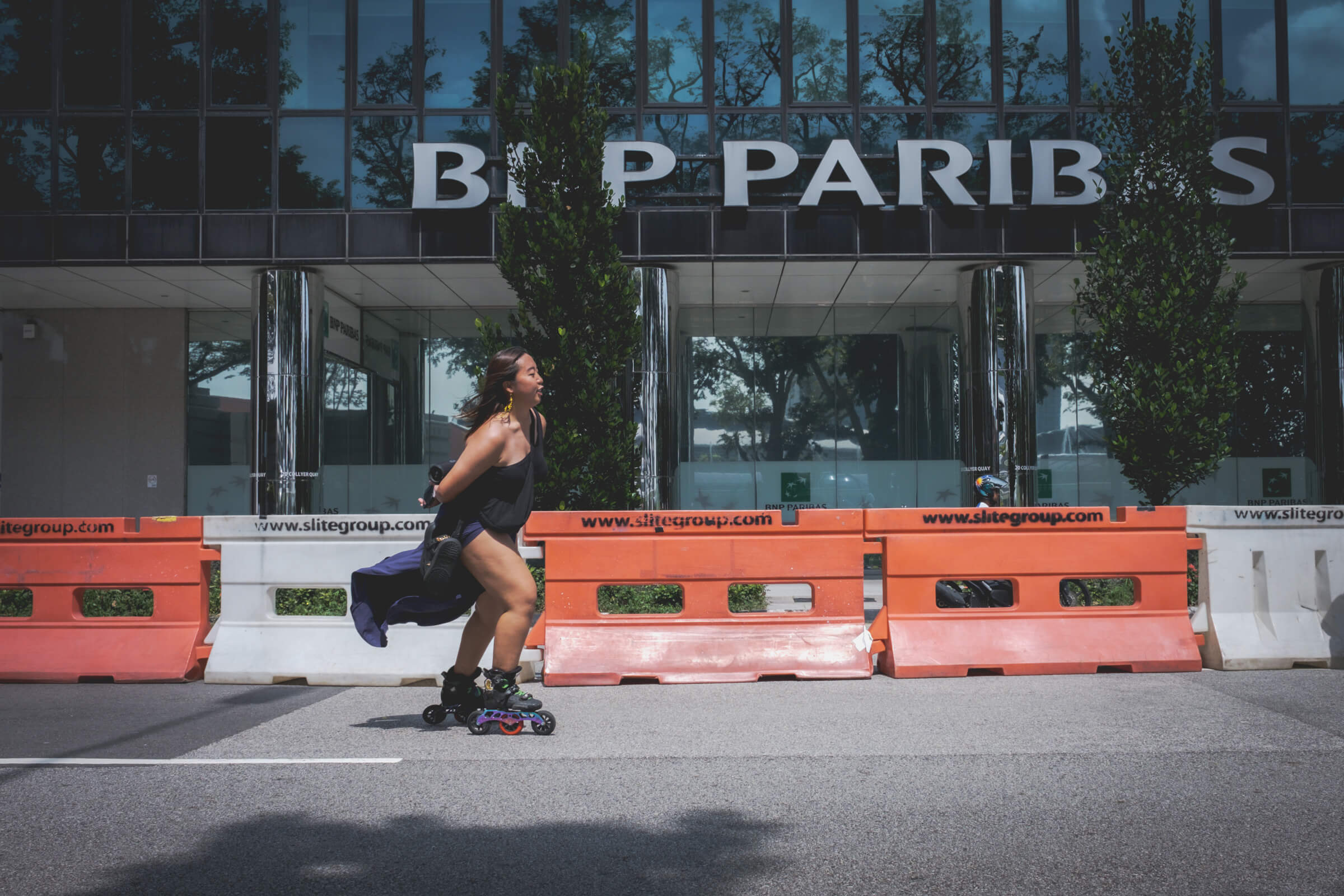 photo of a person wearing a black dress while roller blading on a car-free street