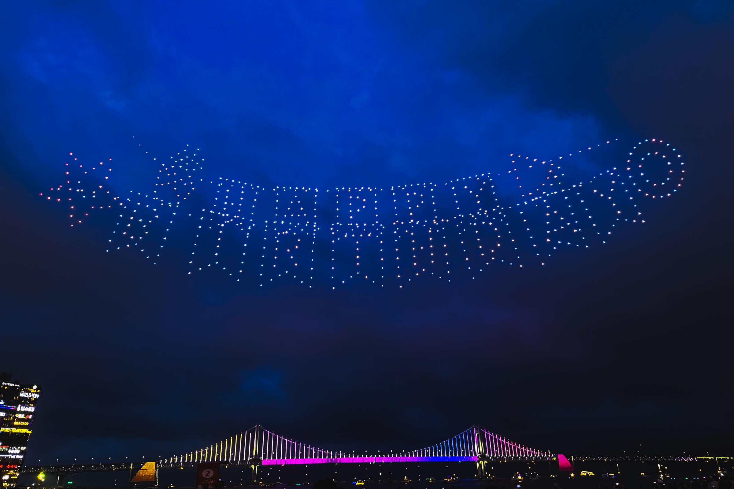 photo of a drone light show making a "happy birthday" formation