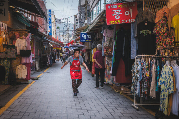 photo of a korean ahjumma delivering food delicately balanced on her head in a market
