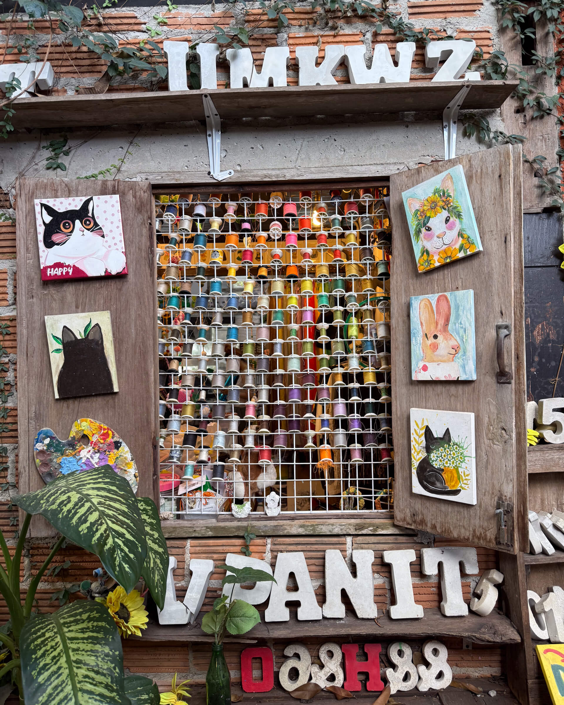 photo of a display of threads at window with several paintings