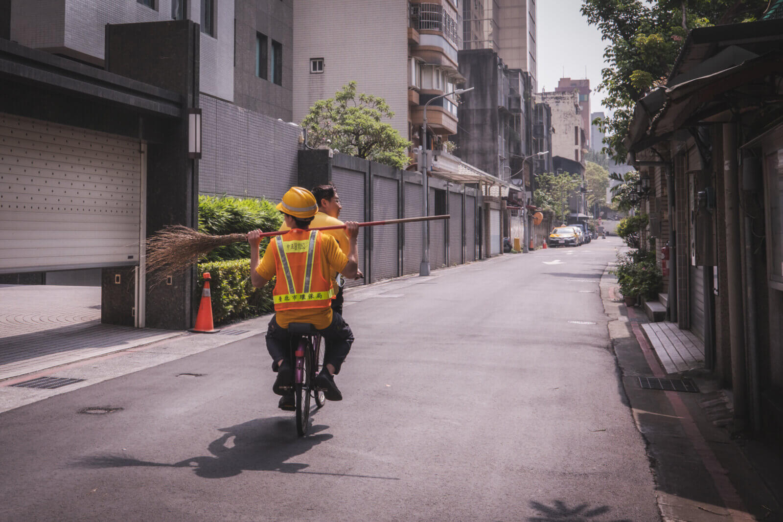 photo of a someone carrying a broom, being ferried on a bicycle