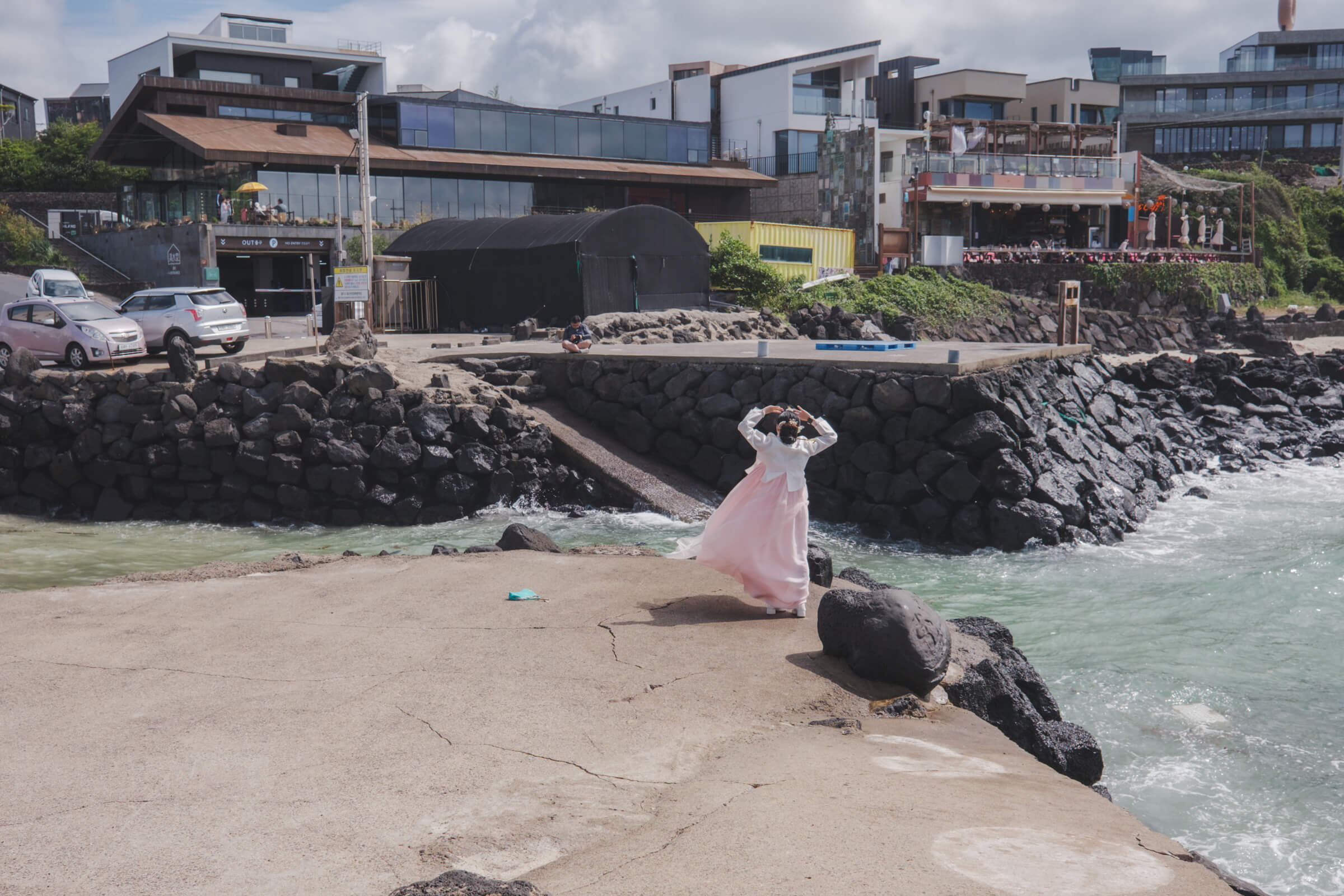 photo of someone posing for a photo in a hanbok, and her photographer is situated across the waters